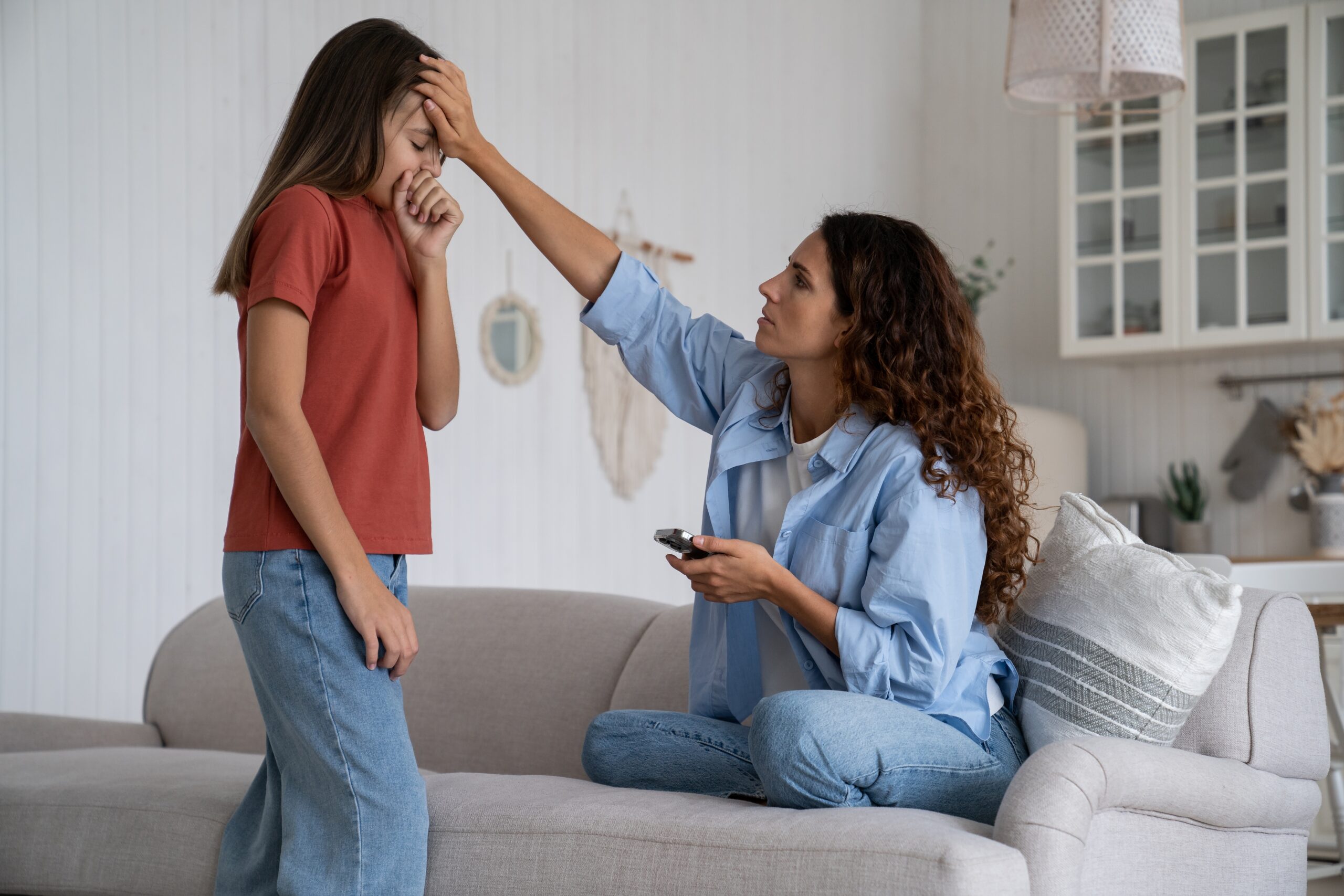 Worried,Mother,Holding,Mobile,Phone,Touching,Forehead,Of,Unhealthy,Coughing